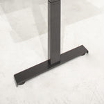 Zwart metalen T-vormige onderstel van ergonomisch elektrisch zit-sta bureau op betonnen vloer. - Elektrisch Zit-Sta Bureau OFI DYNAMO – NPR 1813 & Ergonomisch - Office Furniture Interior