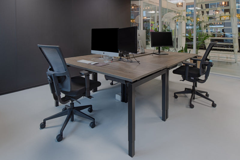 Ergonomische bureaustoel met zwarte mesh rugleuning en verstelbare armleuningen aan bureau. - Bureaustoel OFI FLEX – Ergonomisch NPR 1813 - Office Furniture Interior
